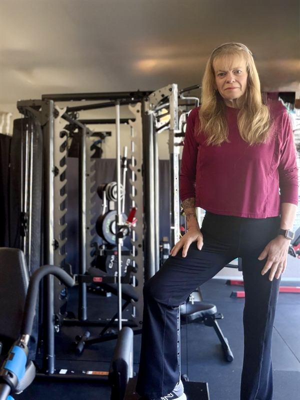 Erica standing beside the power rack in her garage studio