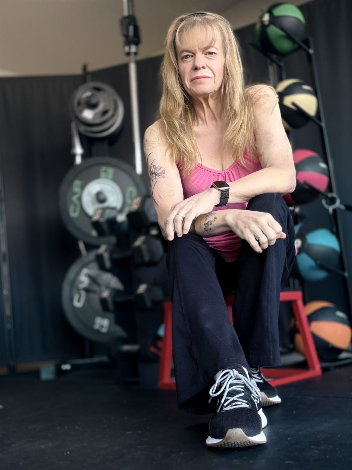 Erica, founder and coach of POWHER Strength Studio, sitting in the studio in front of the weight racks