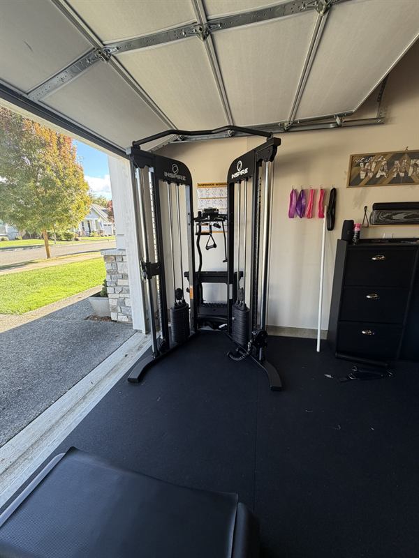Dual-cable functional trainer in front of the open garage door