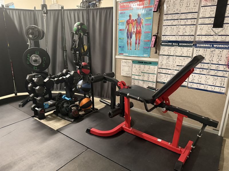 Dumbbell and plate racks next to a red adjustable weight bench